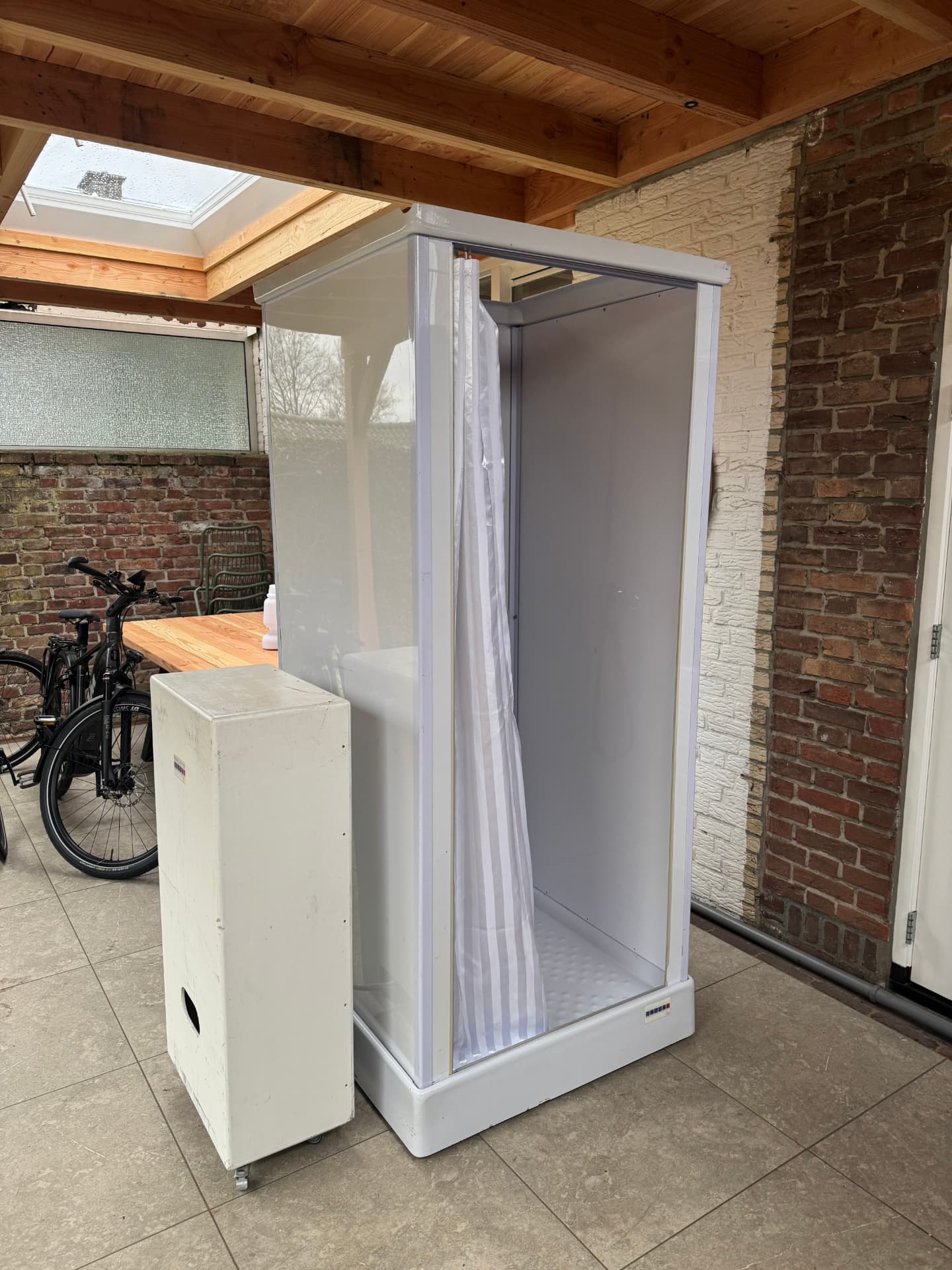 Mobiele douchecabine met mobiele boiler onder een overkapping in Geleen