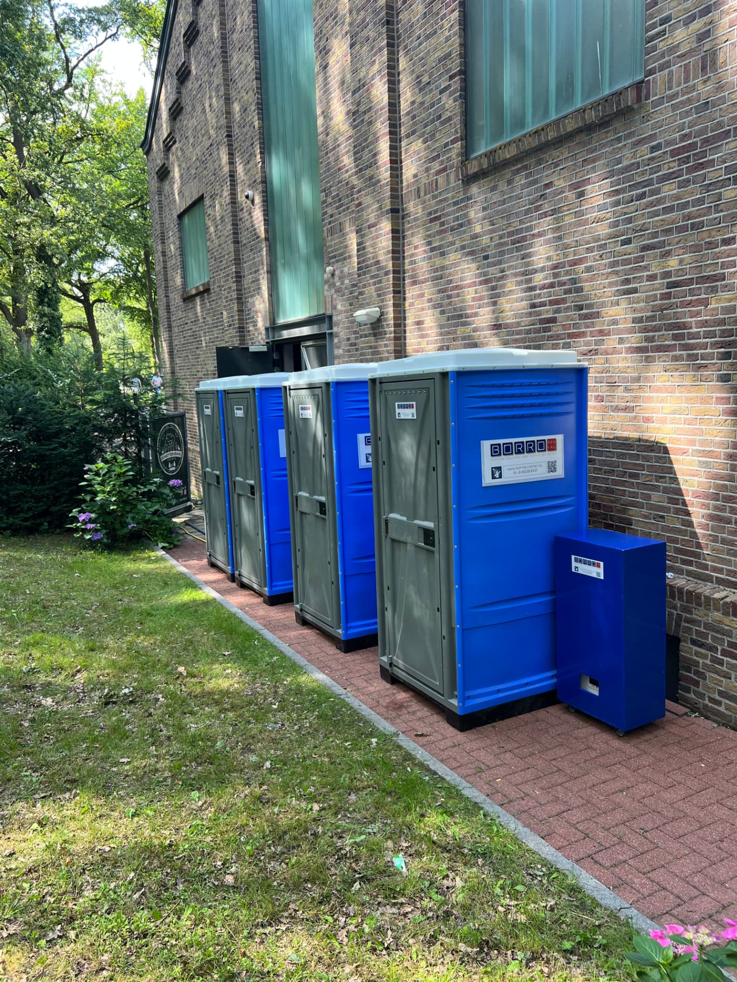 Rij mobiele douchecabines met mobiele boiler tegen de gevel in het Schutterspark in Brunssum