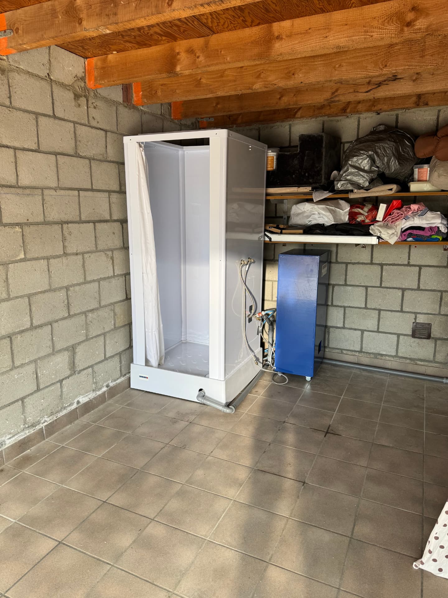 Mobiele douche met boiler in garage tijdens herstel na brandschade