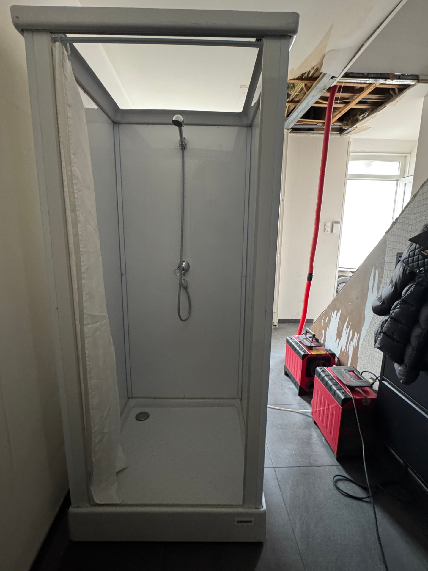 Mobiele douchecabine van Borro-Rental in de gang van een woning in Kerkrade-Centrum tijdens waterschade