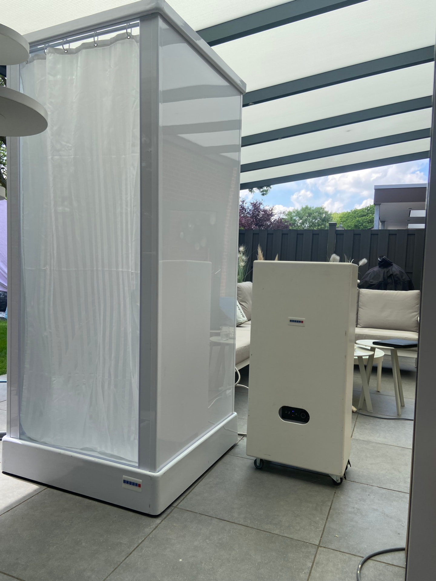 Mobiele douchecabine met douchegordijn en mobiele boiler onder een overkapping in Brunssum