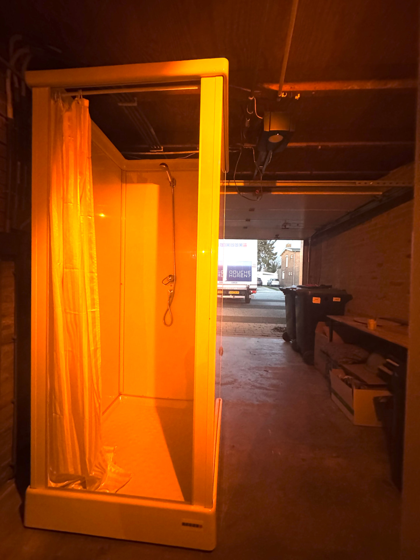 Tijdelijke douche met mobiele warmwatervoorziening geplaatst in een garage